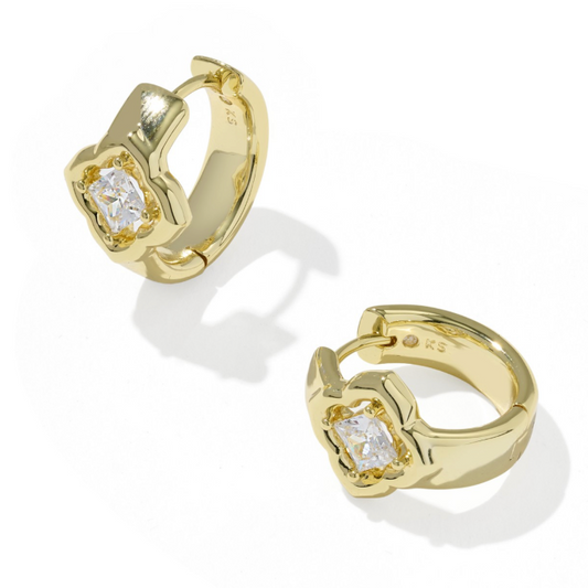 A pair of gold huggie hoop earrings with a central square-cut clear gemstone, displayed on a clean white background with soft shadows.